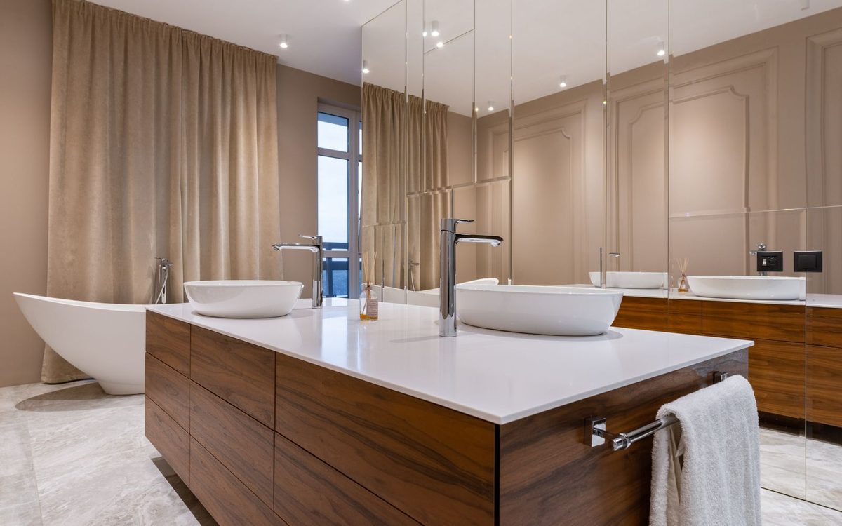 Primary bathroom with clear counters, a big polished mirror, and a freestanding tub