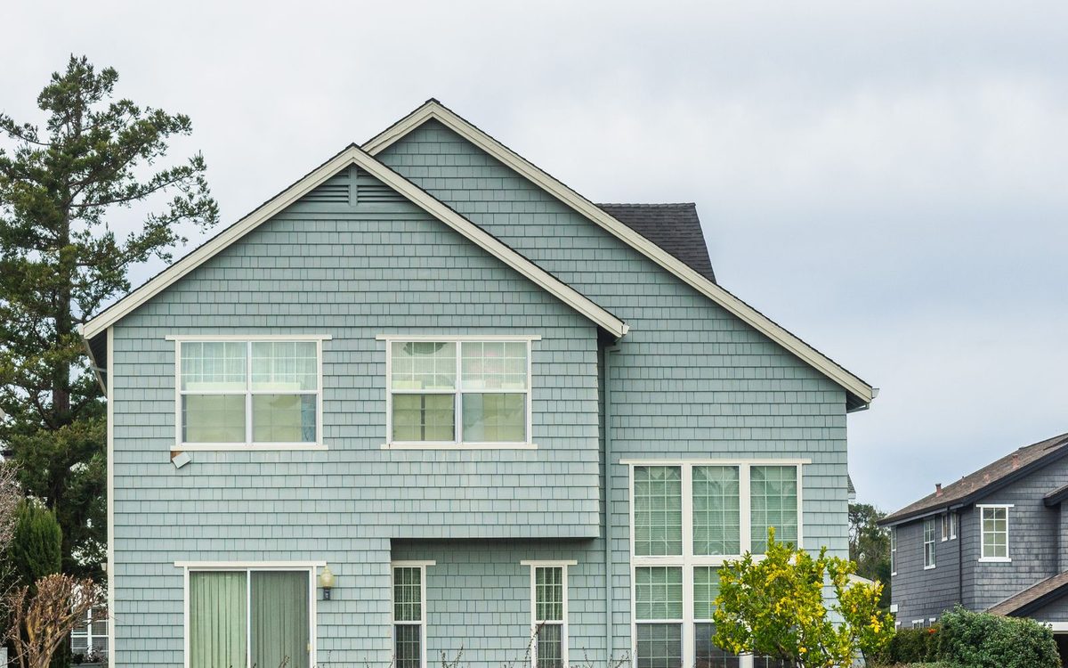 Front of a tidy home with a mowed lawn and a trimmed hedge