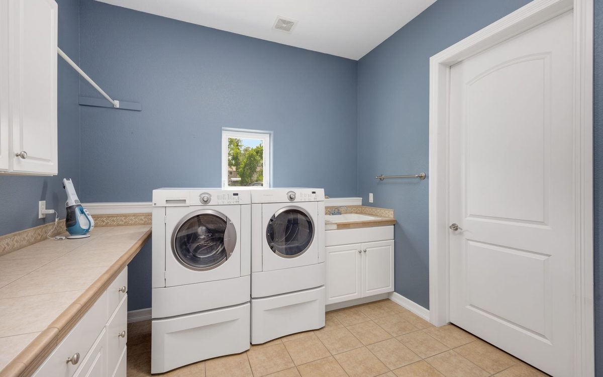 Laundry room with wiped-down machines, clear counters, and cabinets