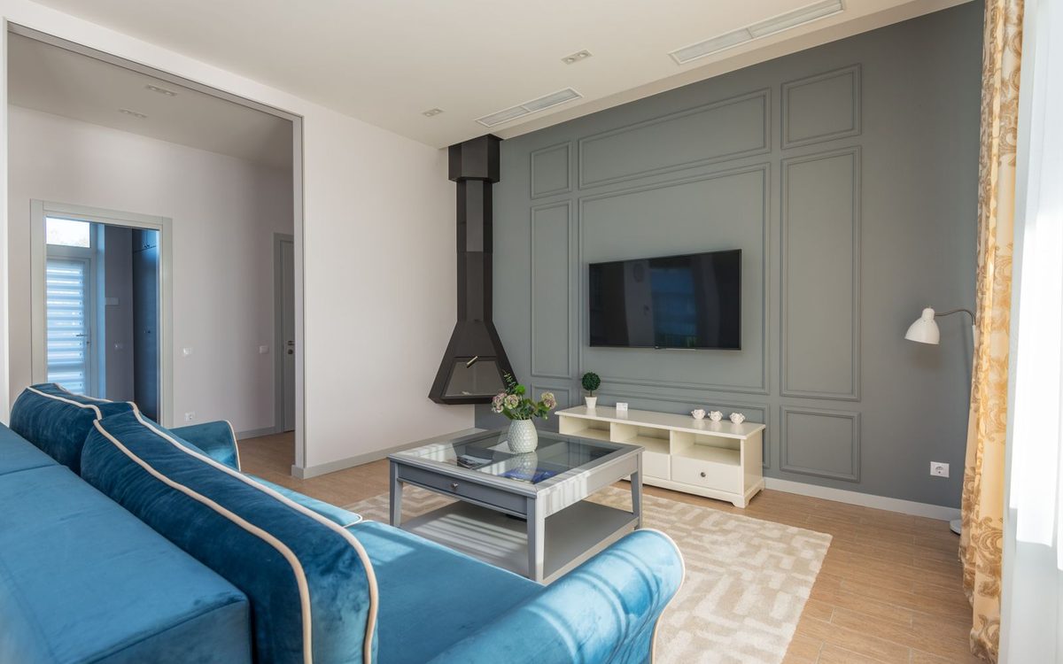 Staged living room with a sofa facing a simple TV wall, a coffee table, and a rug