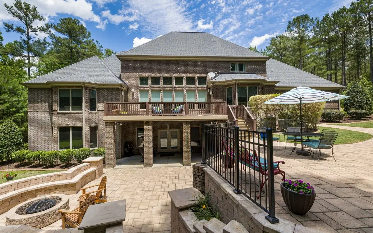 Wide photo of the back of a home with a swept patio, set out like a listing photo